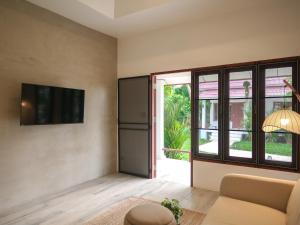 ein Wohnzimmer mit Sofa und Fernseher in der Unterkunft Tropical Nusa Residence in Koh Samui 