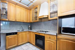 a kitchen with wooden cabinets and a sink and a microwave at ApartLux Belorusskaya Suite in Moscow