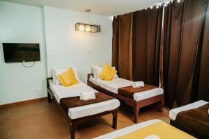 a room with two twin beds and a tv at Villa Rosita Hotel Naga City by RedDoorz in Naga
