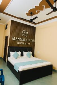 a bedroom with a bed with a sign on the wall at Mangalayatan Home Stay Ayodhya in Faizābād