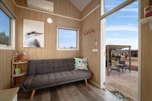a living room with a couch and a patio at Bluestone Alpacas The Alpaca Deluxe by Tiny Away in Merbein