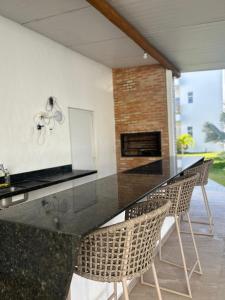 a kitchen with a black counter top and chairs at Condomínio Vila do Mar in Luis Correia