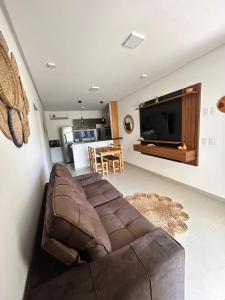 a living room with a brown couch and a flat screen tv at Condomínio Vila do Mar in Luis Correia +33 photos