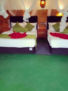 two beds in a room with green flooring at Serenity cottage in Ella