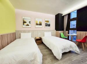 a bedroom with two beds and a chair and a window at Yours Inn Luodong in Luodong