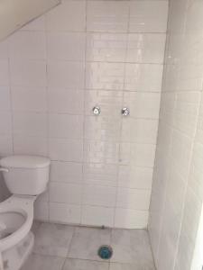 a white tiled bathroom with a toilet and a shower at Suite Reforma in Oaxaca City