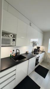 a white kitchen with a sink and a microwave at LUXE, by Ilona Apartments in Kotka