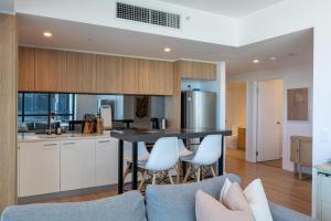 a kitchen with white cabinets and a table and chairs at Luxury Apartment on Franklin-3BD in Adelaide