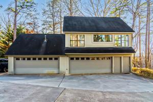 una casa blanca con techo negro y garaje en Modern Treehouse with Views and Comfort, en Lake Hamilton