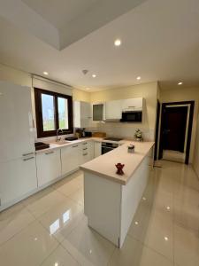 a large kitchen with white cabinets and a counter top at هوانا ڤيو - Hawana view in Ma‘mūrah