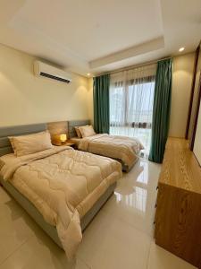 two beds in a bedroom with green curtains at هوانا ڤيو - Hawana view in Ma‘mūrah +21 photos