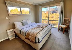 a bedroom with a bed and a window and a chair at Askray Apartment - Lake Tekapo in Lake Tekapo +5 photos