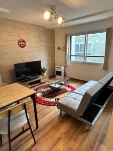 a living room with a couch and a tv at Satisfy サティスファイ in Chitose