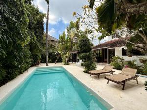 einen Pool mit zwei Stühlen neben einem Haus in der Unterkunft Villa White Orchid Seminyak in Seminyak