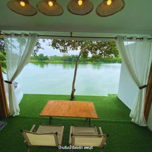 a room with a table and chairs and a view of a river at Baanrimnam Resort Lopburi in Chai Badan
