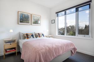 a white bedroom with a bed and a window at StayCentral - The Park Port Melbourne in Melbourne +16 photos