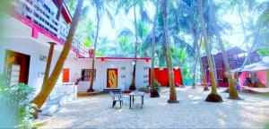 Un patio con mesa y sillas y palmeras. en Samant Beach Resort, en Malvan