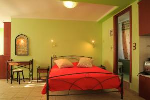 a bedroom with a red bed and a table at To Asteri in Avgonyma