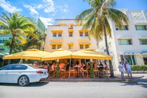un coche blanco estacionado frente a un restaurante con sombrillas amarillas en Casa Grande Suites on Ocean Drive, en Miami Beach