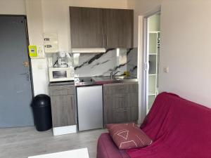 eine kleine Küche mit einem lila Sofa in einem Zimmer in der Unterkunft Studio tout équipé pour 2 a 15 minutes de valras plage in Béziers