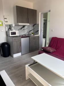 ein Wohnzimmer mit einem roten Sofa und einer Küche in der Unterkunft Studio tout équipé pour 2 a 15 minutes de valras plage in Béziers