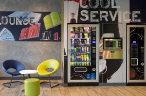 a restaurant with a soda vending machine and two yellow chairs at ibis budget Montceau les Mines in Montceau-les-Mines