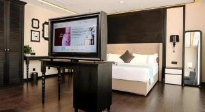 a bedroom with a bed and a television on a desk at Xana Hotelle·Ji'nan Hi-tech Zone Century Avenue Tangye in Jinan +170 photos
