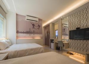 a hotel room with two beds and a flat screen tv at 寓旅宿 Apato Cityhome in Kaohsiung