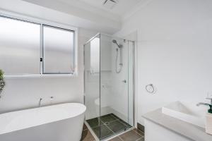 a white bathroom with a tub and a glass shower at Swell in North Creek