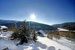 a snow covered mountain with the sun in the sky at Pension Karolína in Špindlerův Mlýn