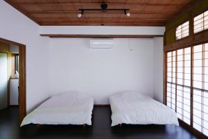 two beds in a room with two windows at ふなだけの家 in Shinano