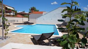 a swimming pool with chairs next to a building at Apartments Roberta in Kožino