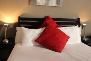 Una cama con dos almohadas rojas encima. en Flamboyant Guest Lodge, en Johannesburgo