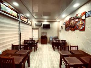 a restaurant with wooden tables and chairs and a television at Elegant Hotel in Tashkent