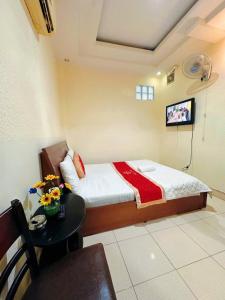 a bedroom with a bed and a table and a tv at Khách Sạn Ngọc Hà in Ho Chi Minh City