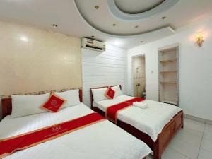 a bedroom with two beds with red and white sheets at Khách Sạn Ngọc Hà in Ho Chi Minh City