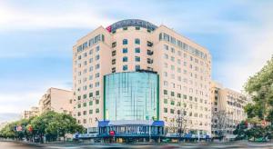 a large white building with a bus in front of it at Echarm Hotel Changsha Wuyi Square Xiangya 2nd Hospital Metro Station in Changsha