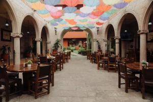 a restaurant with tables and chairs and a ceiling with umbrellas at Hotel Mesón de los Cristeros 