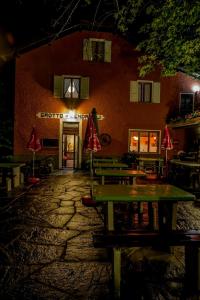 um restaurante com mesas e guarda-sóis em frente a um edifício em Grotto Zendralli em Roveredo