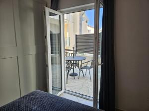 a bedroom with a bed and a balcony with a table at Apartmani Katja in Omiš