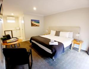 a hotel room with a bed and a table and a desk at Higgins Lane Motel in Margaret River Town