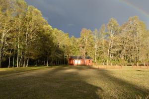 a barn in the middle of a field with a rainbow at Cabañas Valle del Río in Curacautín