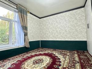 a bedroom with a rug on the floor and a window at Shahzod Guesthouse & Homestay in Gelen