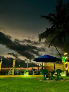 a table and chairs with an umbrella and a palm tree at The Family Beach Villa in Uswetakeiyawa