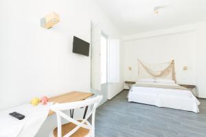 a white bedroom with a bed and a desk at Tangram House in Pulsano