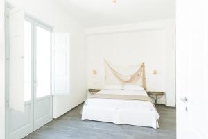 een witte slaapkamer met een bed en een raam bij Tangram House in Pulsano