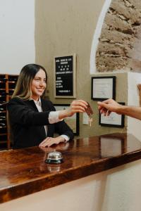a woman is sitting at a table handing a key to another woman at Hotel Mesón de los Cristeros 