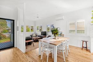 a white dining room with a table and chairs at Amaroo - Pet Friendly - 2 Mins Walk to Beach - Outdoor Fireplace in Culburra Beach