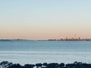 a large body of water with a city in the background at Auckland Sunrise Sea View in Auckland