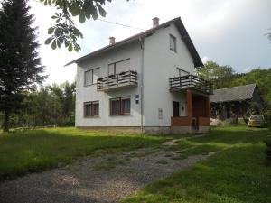 a white house with windows and a yard at Apartman Došen in Ličko Petrovo Selo